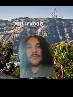 The cover image shows a man in front of the Hollywood sign, overlaying his face against the scenery. The sky is blue, and the Hollywood sign is on a green, natural hillside. The man has long, wavy dark hair and a mustache.