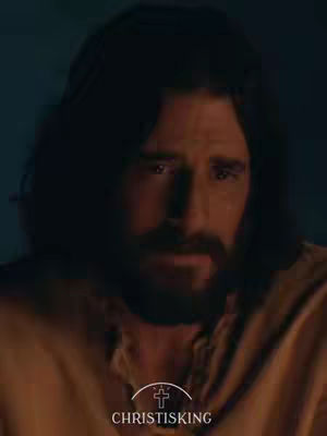 The image is a close-up of a man with dark hair and a beard. He is wearing a brown garment. The background is a dark, muted color. The overall composition is designed to highlight the subject's face and expression, suggesting thematic content related to Christianity.