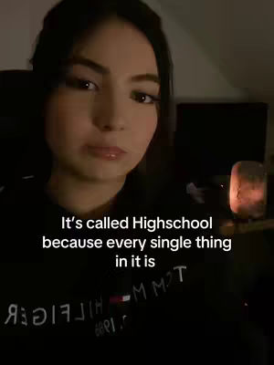 The cover image features a young woman in a close-up shot, facing the camera with a somewhat serious expression. Text overlayed on the image reads, "It's called Highschool because every single thing in it is." Behind the woman are blurred dark elements, with a warm light source on the right side of the frame.