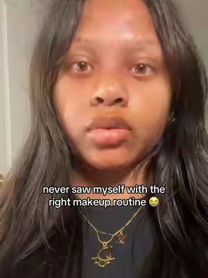 A close-up shot of a young Black woman with long, dark hair. The woman is looking at the camera with a neutral expression. She's wearing a black top and a gold necklace. Text overlay reads' never saw myself with the right makeup routine'.