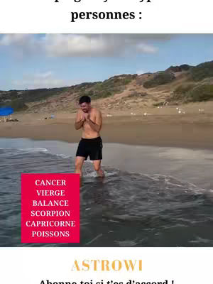 A man stands in the shallow water of a beach, appearing cold. He is bundled up, shivering by the seashore. A red rectangular box is superimposed on the image with the names of several Zodiac signs. The background includes the beach, ocean, sky, and sand area.