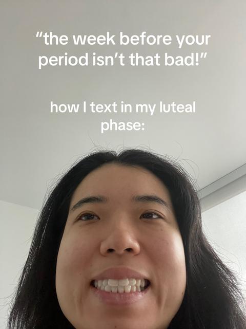 A selfie-style image featuring a woman looking up at the camera with a wide smile, set against a plain, pale background. The woman has long, dark hair and is positioned from the mid-chest up. Text overlays are present in the upper portion and the center of the frame in a white, sans-serif font, with the text indicating the phase of the menstrual cycle discussed in the text.
