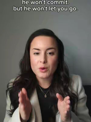 A woman with long dark hair and a beige blazer gestures with her hands while speaking, with text overlaying the top that says, "he won't commit. but he won't let you go."