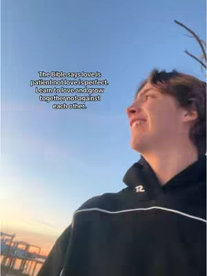 A young man with light skin smiles toward the upper-right corner against a blue-sky background. He wears a black hoodie with white accents. Text overlays are present on the top left.