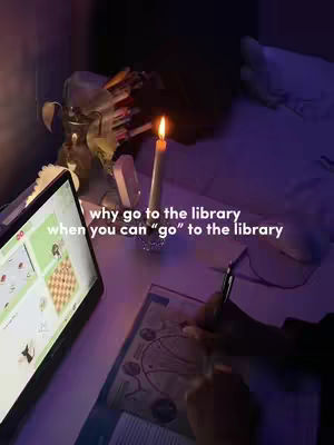 An indoor scene, dimly lit, showcasing a workspace. A lit candle sits on a table along with stationery, and a laptop on the left. Text overlayed expresses a question, with a playful take on going to the library.