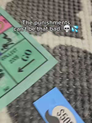 The image shows a top-down view of the game Monopoly. A green property card, blue card with a mustache and $500, and a textured gray surface fill most of the frame. The text overlay at the top says "The punishments can't be that bad.." with a skull and water droplet emojis.