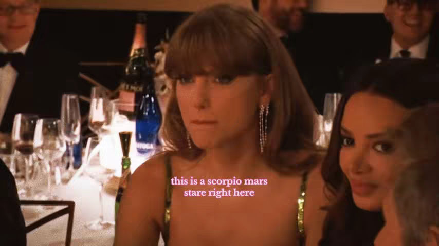 The image shows a woman, likely at the Golden Globes, situated at a table setting. She is wearing an elegant dress, has long hair, and is looking somewhat pensively into the distance. Text overlayed on the image reads, "this is a scorpio mars stare right here".