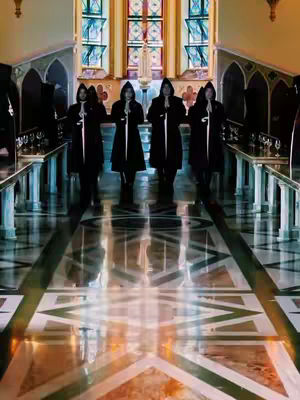 The image showcases a church interior with a highly reflective polished floor, leading the eye towards a stained-glass window. Four figures, dressed in black hooded robes, stand in a line, holding what appear to be thin, silver swords upright in front of them. The color palette is dominated by dark, muted tones with rich gold and warm light emanating from the windows.