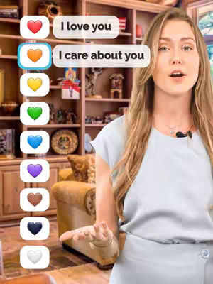 A woman stands in front of a wooden bookcase giving a presentation. Floating next to her are bubbles containing different colored heart emojis with associated text. The background is a cozy, well-lit room.