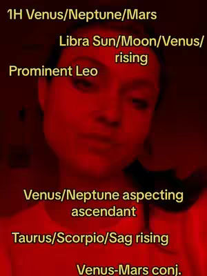 A selfie with a heavily red-tinted filter. The person's face is the primary focus. Text overlays detail astrological placements in a gold font.