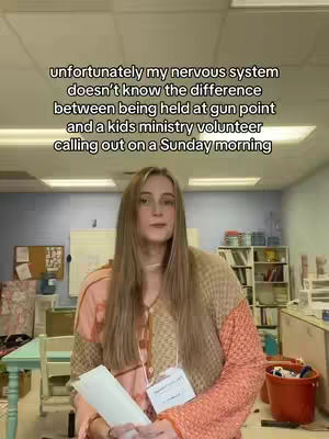 A woman with long blonde hair stands in a room, facing the camera. She holds a paper, and a name tag is visible. The background includes shelves, a whiteboard, and other items, likely in a ministry or office setting. Text overlay at the top.