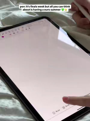 The image shows a close-up of a tablet on a bed. A hand with a pen is in the upper right corner and a finger is touching the screen in the bottom right. The screen displays a digital notepad with text overlayed at the top about finals week and a Euro summer. The background appears to be a light-colored bedspread.