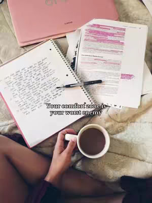 A photo taken from a point-of-view of a person studying, with a cup of coffee to the right, and notes in front of the person, as well as a pink laptop in the background.