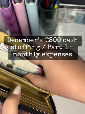 The cover image shows a pair of hands holding a wallet with visible banknotes, alongside binders, pens, and other money-related accessories. The background includes a glimpse of shelves and other stationery items, and a text overlay provides the video's title.