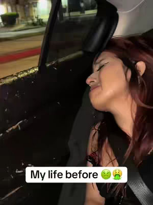 A woman seated in a car is the main focus, visible from the side, with her head turned towards the camera. She appears to be crying, with visible tears and a slightly distressed expression. The interior of the car is dark, with the frame of the car door and the outside environment partially visible. The window next to her reflects some of the nighttime lights. The image uses an expressive facial shot to create a reflective message.