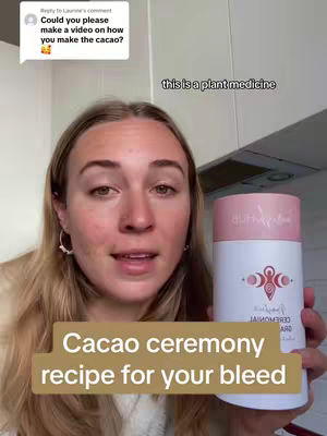 A woman with blonde hair is centered in the frame, holding a white and pink cylinder labeled 'Peruvian Ceremonial Cacao'. She is smiling and speaking, with overlaid text at the bottom reading 'Cacao ceremony recipe for your bleed'. A comment from someone is in a text box on the left, asking for a video to show how to make cacao and another text bubble says 'this is a plant medicine'. The background appears to be a kitchen.