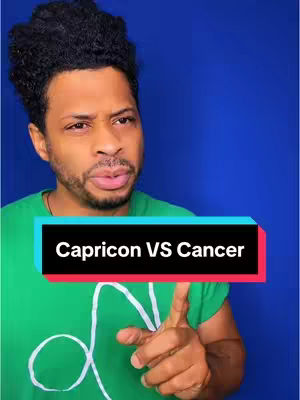 A man with short, dark curly hair, wearing a green t-shirt, gestures with his right index finger whilst looking towards the left. The background is a solid blue. A black and red text box at the bottom of the shot reads "Capricorn VS Cancer".