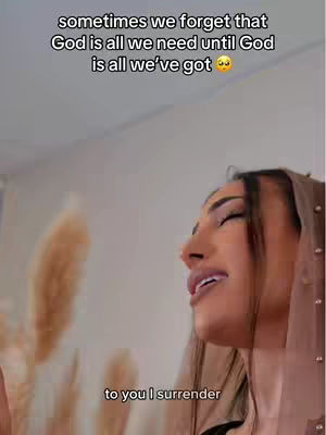 The cover image features a woman with dark hair and makeup in a close-up shot. She appears to be looking upwards with eyes closed and mouth slightly open, possibly in a moment of prayer or reflection. The background is softly blurred, with some feathery objects visible on the left side of the frame. Text overlays are present at the top and bottom with a message about God.