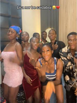 A group of young women and men are gathered indoors, likely at a social event. The image is a candid shot, possibly a video still, with a warm lighting that seems to be from an indoor fixture. The background is somewhat blurred, and the focus is on the people in the foreground.