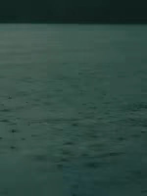 The cover image shows a body of water under a dark, overcast sky. The water surface is rippled with small, dark disturbances, possibly raindrops or gentle waves, and the scene is rendered in a muted, teal and dark green color palette, creating a tranquil yet slightly somber atmosphere. The horizon line is clearly defined, dividing the sky and water.
