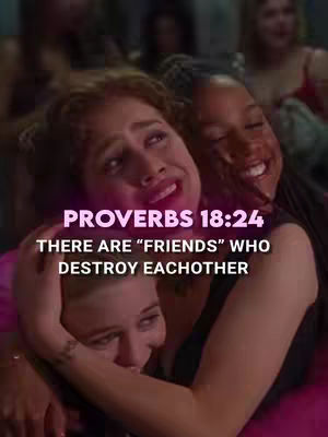 The image shows a tight shot of four young women huddled together, their heads close to each other. The central figure is in the center with her face lifted up towards the viewer with an expression reflecting sadness or emotional distress. Two other women are comforting her, with one on each side, holding her and smiling warmly. The background is blurred, dark and out-of-focus, suggesting an indoor setting, possibly a party.