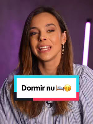 The cover image shows a woman with long brown hair facing the camera. She is smiling with her mouth open, and blue and pink neon lights are in the background. A text overlay at the bottom spells out'Dormir nu' in bold white letters against a blue and red rectangle. A bed and a smiling face emojis is on the end of the text.