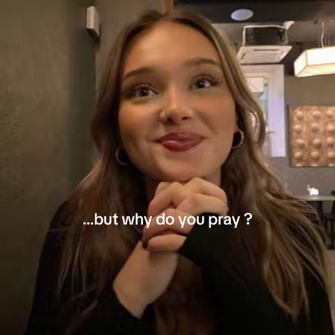 The cover image features a close-up of a young woman indoors. She is looking up and to the right, with eyebrows raised and a slight smile, suggesting thought or contemplation. The woman has long, light brown hair and is wearing hoop earrings and a black top. A subtle text overlay at the bottom reads, "…but why do you pray ?". The background is a mix of indistinct shapes, potentially indicating an indoor setting like a restaurant or a cafe.