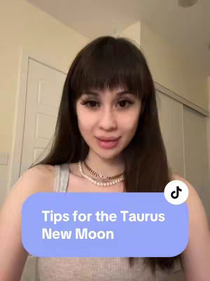 The cover image shows a woman with long, dark hair and a layered fringe, smiling at the camera. She's wearing a gray top and a pearl necklace. A light blue rectangle at the bottom of the image contains the text "Tips for the Taurus New Moon." A TikTok logo is present in the top right corner.
