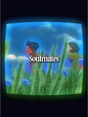 An animated image framed within a simulated television screen. The scene depicts two anime-styled characters, a boy with dark hair and a girl with shorter dark hair. They appear to be standing in a field of tall, green grass interspersed with blue flowers. The background fades into a gradient of blue and a few visible stars. The word 'Soulmates' is superimposed in the center of the image, in white font with a black outline.