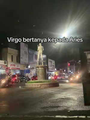 A nighttime street scene with a statue illuminated on a roundabout. Text is overlaid on the image.