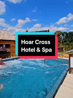 The image shows an outdoor spa setting with a turquoise pool. A text overlay reading 'Hoar Cross Hotel & Spa' is at the center, enclosed in a black box with cyan outline, over an image of the spa's pool. The pool has water and a silver metal hand rail. The sky is blue with fluffy white clouds and various trees are visible.