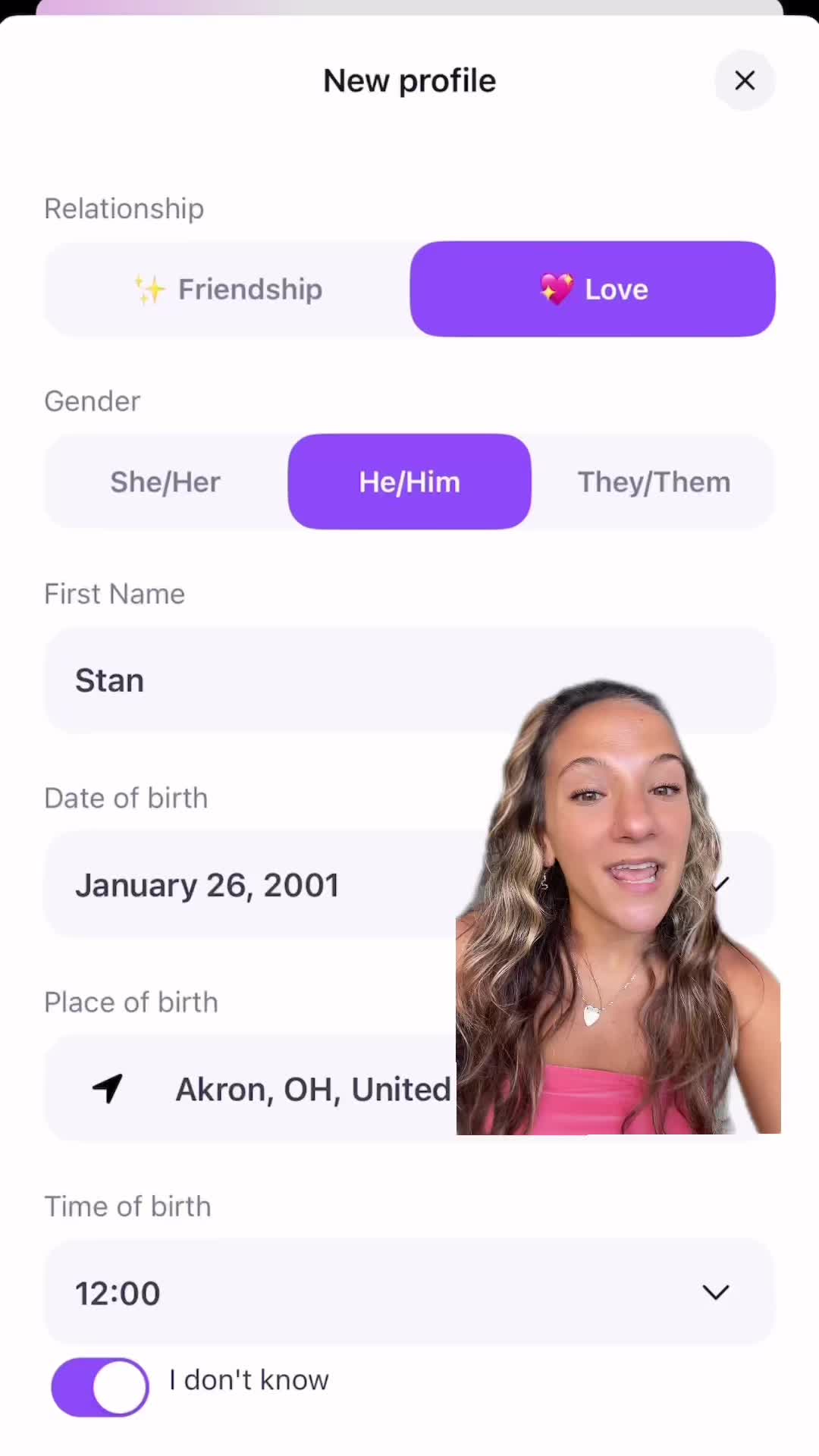 The image shows a woman in a half-length shot, centered, smiling and speaking with a phone interface overlaid. On the interface for a dating app, the user is prompted to fill out her profile. The app interface features a 'New profile' header, options for 'Relationship', 'Gender', 'First Name', 'Date of birth', 'Place of birth', and 'Time of birth'.