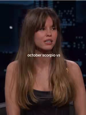 The cover image features a woman with long brown hair, bangs, and a dark top. Text overlayed on the image reads "october scorpio vs". The background is a blurred interior.