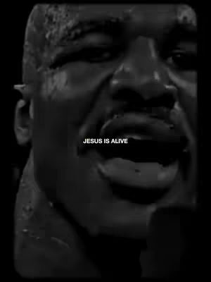 A black and white image showing a close-up of a man's face with a strong expression. The background is dark, which emphasizes the details and emotion on the man's face. The text "JESUS IS ALIVE" is overlaid on the image.