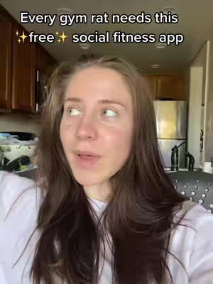 A woman with long brown hair poses in front of a kitchen. Text overlays at the top read: 'Every gym rat needs this, free social fitness app.'