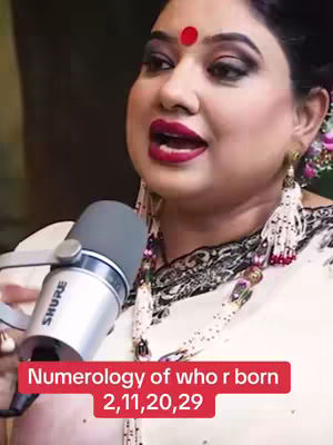 The cover image features a woman speaking into a microphone. She has heavy makeup, a red bindi, and is wearing a white outfit with a decorative necklace. Text at the bottom reads, 'Numerology of who r born 2,11,20,29.'