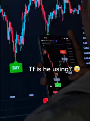 The image shows a person holding a smartphone displaying a stocks trading chart on its screen. Behind the smartphone there's a larger screen illustrating a stock chart. The phone shows indicators with SELL and BUY labels on chart, suggesting a trading platform. The background has a dark color with clear graphics.