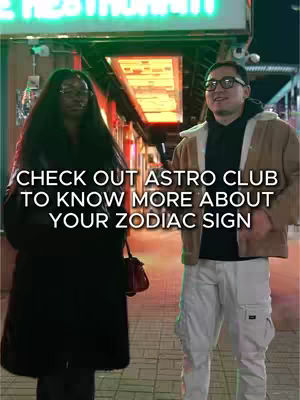 The cover image of this video captures a street scene featuring two individuals standing outdoors. The primary focus is on a woman on the left and a man on the right, standing in front of a storefront with neon signage. The image has a focus on them, hinting that they are the central figures of the content. The lighting is bright, contributing to a clear view of the subjects and their surroundings, and it is likely a low aperture photo judging from the background blur.