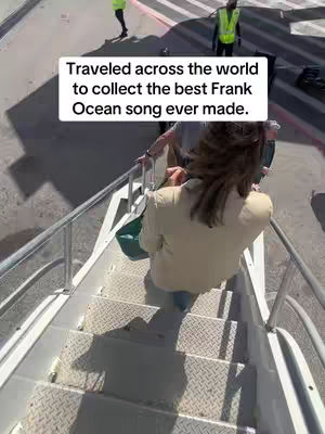 A person descends a set of metal stairs with a handrail. A white text box is on top of the video. Other individuals are present in the background. The scene appears to be at an airport or similar transportation hub.