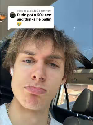 A young man with light brown hair and fair skin is the focal point, captured in a close-up shot. He has a slightly downturned mouth and a neutral expression, with visible ear buds. A speech bubble, positioned in the top left, features text in white font, with an avatar next to it. The background suggests the interior of a vehicle with blue sky. The shot is well-lit, with a shallow depth of field that focuses attention on the man.