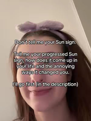 A selfie-style video cover image featuring a young woman with long brown hair, wearing a light purple headband with a bow. The woman's face is centered, and a text overlay in a sans-serif font covers the top half. The background is slightly blurred, suggesting an indoor setting with a visible wall on the right. The overall composition is simple, with the focus on the woman's face and the overlaid text, which poses a question related to sun signs and the ways it changes people's lives.