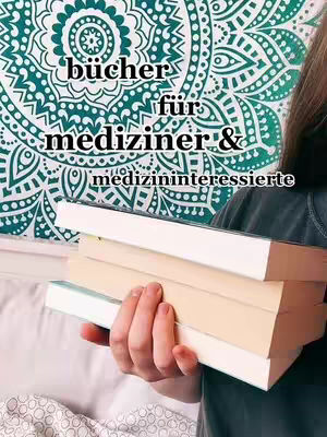 A person is holding a stack of books in front of a patterned tapestry. The books are stacked and held in the person's hands. The background is a patterned tapestry with a symmetrical design in teal and white. The person's arm and part of their shoulder are visible, and they are wearing a dark shirt. Text overlays the image.