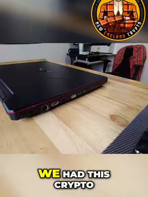 The cover image shows a black laptop on a light wood table. The ASUS ROG laptop covers most the frame in a 3/4 angle shot. In the top right there is a circular logo with the text "NEW ENGLAND CRYPTO." In the background there is a dark wall and the edge of a table . At the bottom of the image are the words "WE HAD THIS CRYPTO" in a yellow rectangle.
