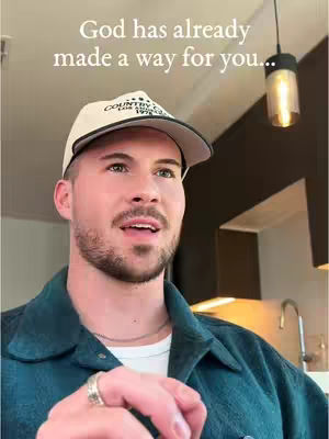 A man wearing a baseball cap and a dark green jacket looks slightly upwards, with text overlayed at the top of the image.