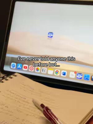 A person is studying at a desk with a laptop open and a notebook and red pen visible.