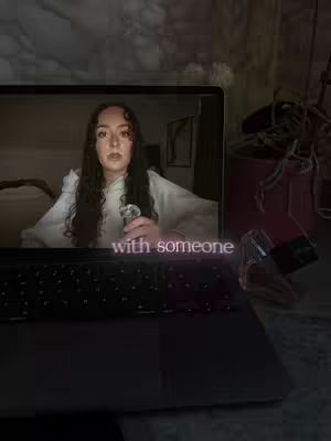 The cover image shows a woman on a laptop screen, appearing as if she's on a video call. The laptop is angled with the keyboard facing the foreground, while a glass with liquid can be seen on the right. The woman is holding an object and seems to be talking. The hook, "with someone", is overlaid on the bottom of the screen.