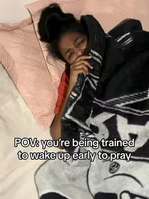 A young woman lies in bed, covered by a blanket, with a distressed expression. The image is composed from a slightly low angle, with a pillow and bed sheets in the background, and a text overlay at the image's bottom.