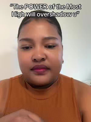 A close-up shot of a woman appearing to be in front of a camera, wearing a brown tank top. Overlayed across her is the text "The POWER of the Most High will overshadow u."