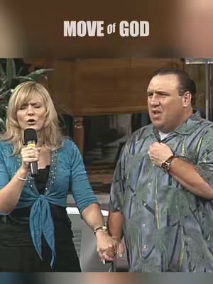 The image features a woman on the left and a man on the right, both holding hands. Behind them is a brown background and some plants are on the left.