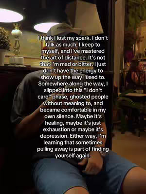 A person seated with visible text overlayed. The person is wearing a hat and a dark-colored shirt. The background is out of focus, but appears to be an indoor space, possibly a restaurant or cafe, with a lamp visible.